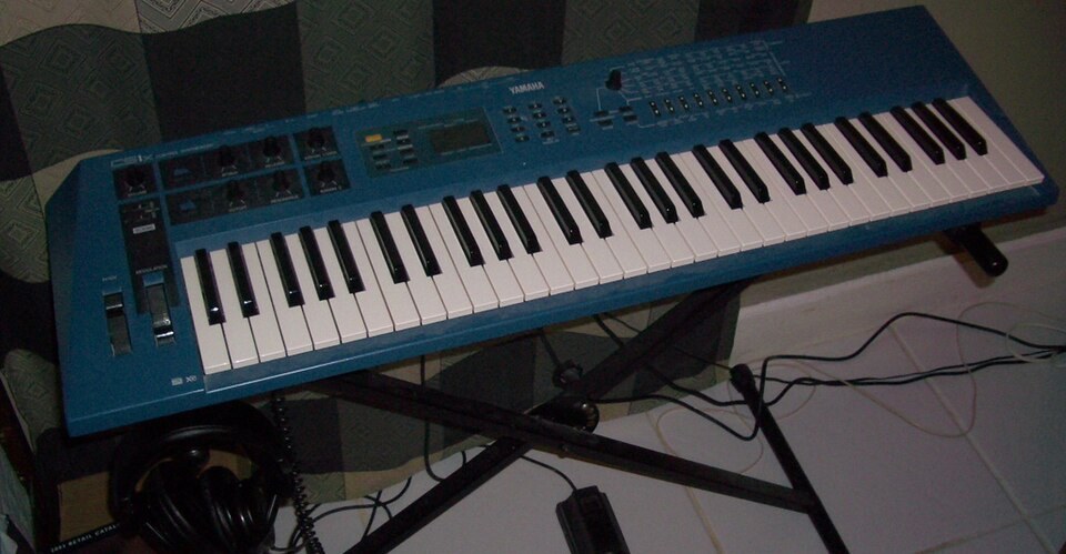 A blue Yamaha CS1x synthesizer on a keyboard stand.