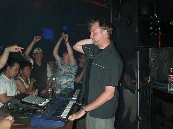 Playing a keyboard next to a small mixer, the crowd right behind.