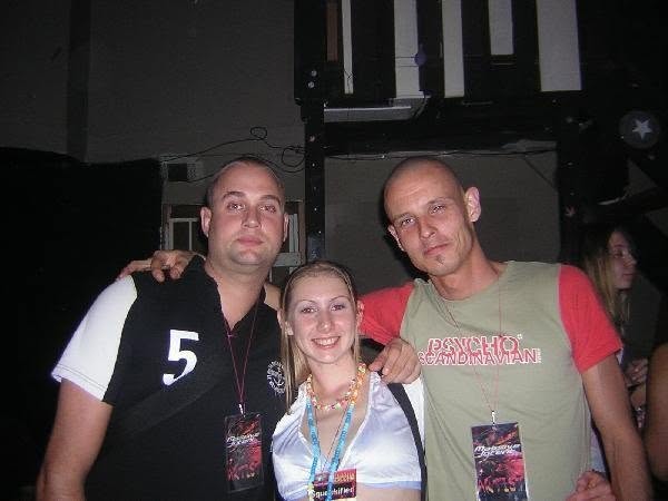 The duo with their artist passes and a smiling woman between them, by the stage.