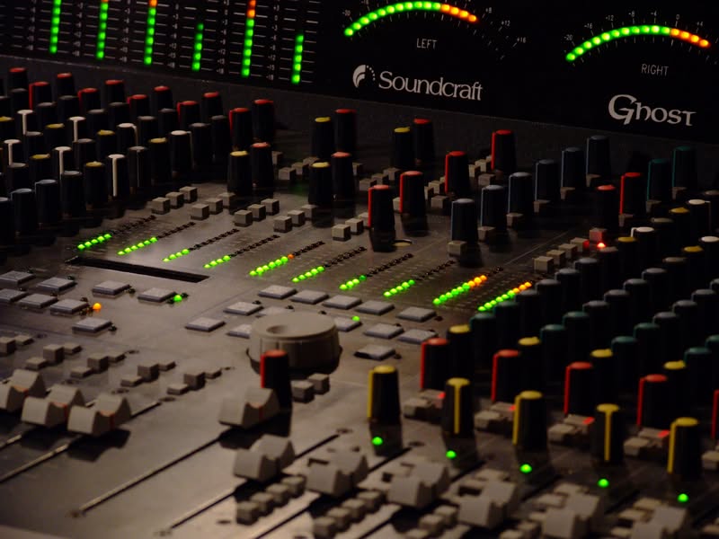 Close-up of a Soundcraft Ghost console with lit level meters and faders.