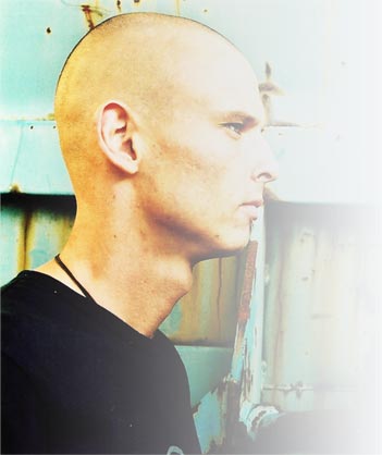 Portrait of Alexander Carlborg (DjC), shaved head, looking to the side, in pale blue light.